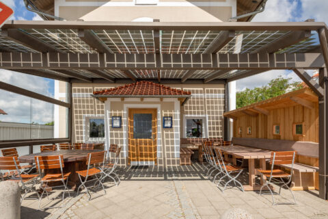 Moderne Gastronomie-Terrasse mit elegantem Aluminium-Terrassendach und integrierten Photovoltaikmodulen zur Stromerzeugung.