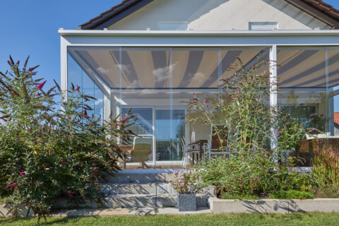 Moderner Kaltwintergarten aus Glas in Oberpframmern als eleganter Wetterschutz für die Terrasse, inklusive integrierter Sonn…