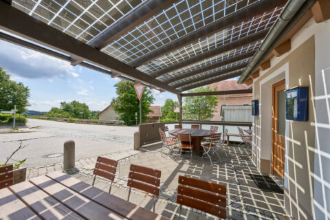 Transparente Terrassenüberdachung mit integrierten Photovoltaik-Modulen spendet Schatten und erzeugt Strom auf der Außenterr…