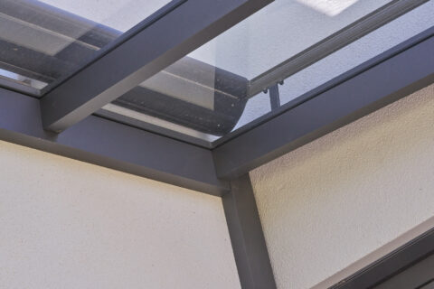 Detaillierter Eck-Wandanschluss einer modernen Terrassenüberdachung aus Aluminium und Glas, präzise montiert.