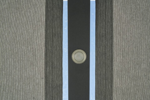 Detailansicht eines modernen Einbaustrahlers in einer grauen Terrassenüberdachung mit Blick zum blauen Himmel.