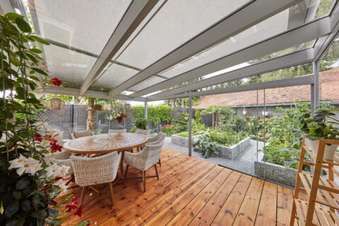 Moderne geschlossene Terrassenüberdachung aus Glas und Aluminium mit integrierter Beschattung, Holzboden, Esstisch und Blick…