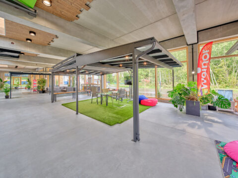 Moderne Terrassenüberdachung mit integrierter Unterdachmarkise und LED-Beleuchtung in einer hellen Showroom-Umgebung von wei…