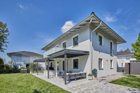 Moderne offene Terrassenüberdachung mit Aufdachmarkisen vor einem Einfamilienhaus in Feldkirchen, München.