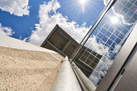 Terrassenüberdachung mit integrierten Photovoltaik-Modulen, die blauen Himmel und Sonnenschein reflektieren. Eine nachhaltig…