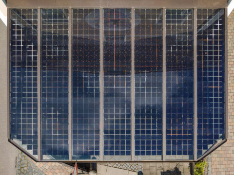 Moderne Terrassenüberdachung aus Glas mit integrierten Photovoltaik-Modulen als Dach von oben gesehen.