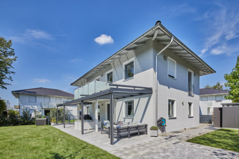 Moderne Terrassenüberdachung aus Glasbau mit integrierter anthrazitfarbener Weinor Aufdachmarkise an einem Einfamilienhaus.