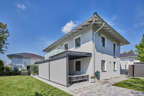 Terrassenüberdachung aus Glas und Aluminium mit integrierten Weinor Seiten- und Aufdachmarkisen an einem modernen Wohnhaus.