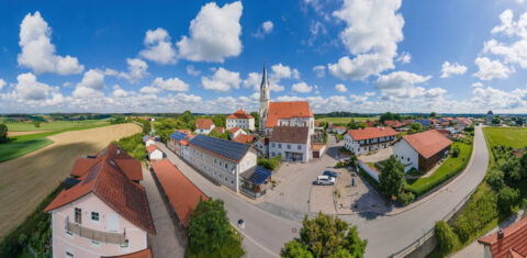 Luftbild von Niederbergkirchen mit Kirche und Wohnhäusern, viele Dächer und Terrassenüberdachungen mit integrierten Solarmod…