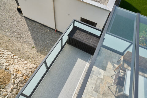 Moderne Terrassenüberdachung aus RAL-beschichtetem Aluminium mit Glasgeländer und -dach für stilvollen Wetterschutz.