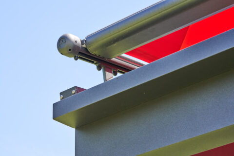 Weinor Ausfallprofil einer Terrassenüberdachung mit integrierter Dachrinne in RAL Farbe, roter Markisenstoff sichtbar.