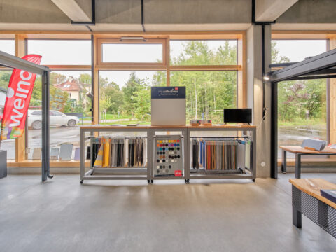 Ausstellungsraum mit Weinor und Warema Markisen-Stoffmustern und Farbfächern für Sonnenschutzberatung.