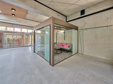 Moderner, freistehender Wintergarten aus Glas und pulverbeschichtetem Marrone-Aluminium in einer Ausstellungshalle.