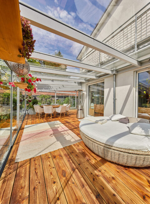 Moderner Glas-Wintergarten mit Holzboden und bequemen Möbeln in Zorneding, ideal für ganzjährige Entspannung und Gastlichkei…